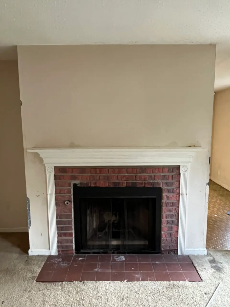 Fireplace before painting: scuffed wall and red brick surround
